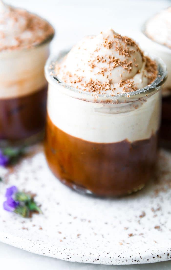 Small glass jar filled with Mexican chocolate mousse, topped with whipped cream and chocolate shavings.