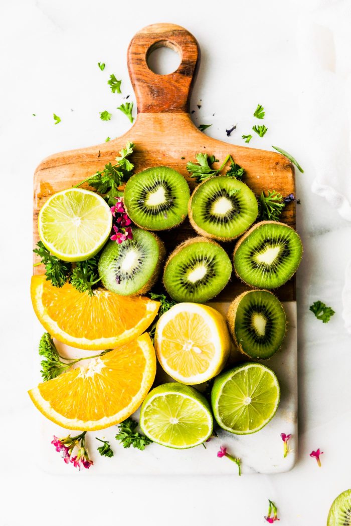 Fresh fruit arranged on wooden cutting board for making green smoothie