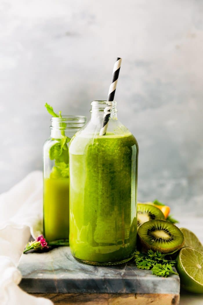 Two tall glass jars filled with super green smoothie, a black and white striped straw in one.