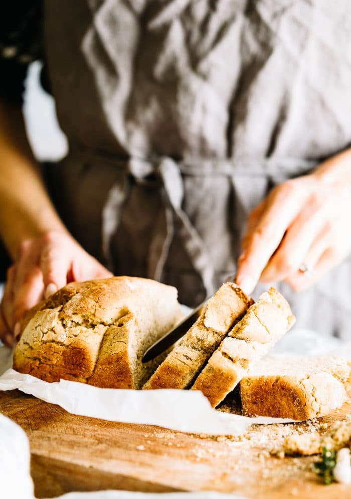 using knife to slice loaf of homemade vegan bread
