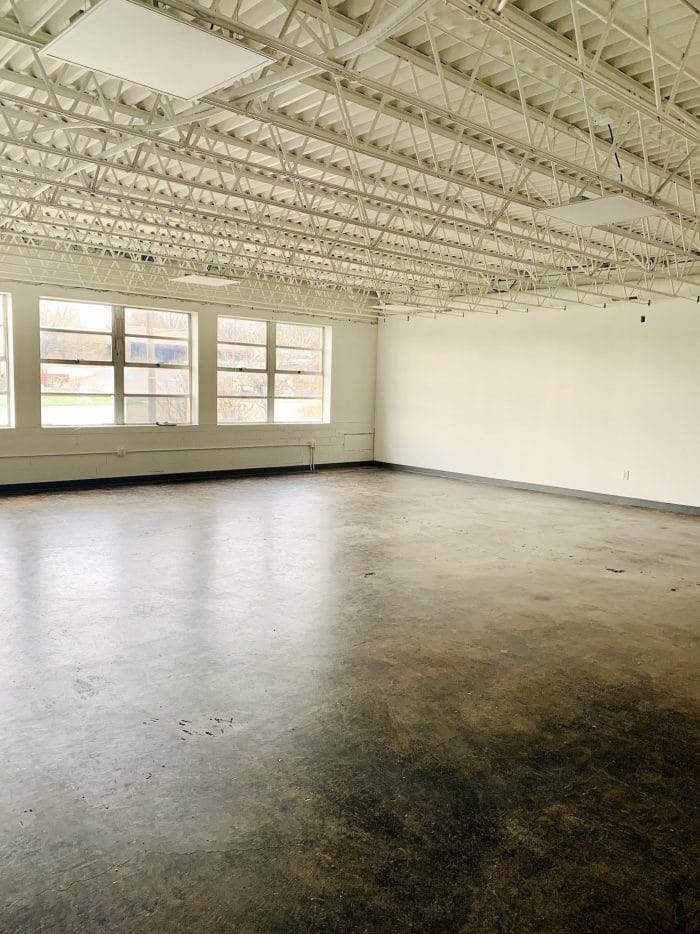Wide open studio space with white exposed ceiling and cement floor