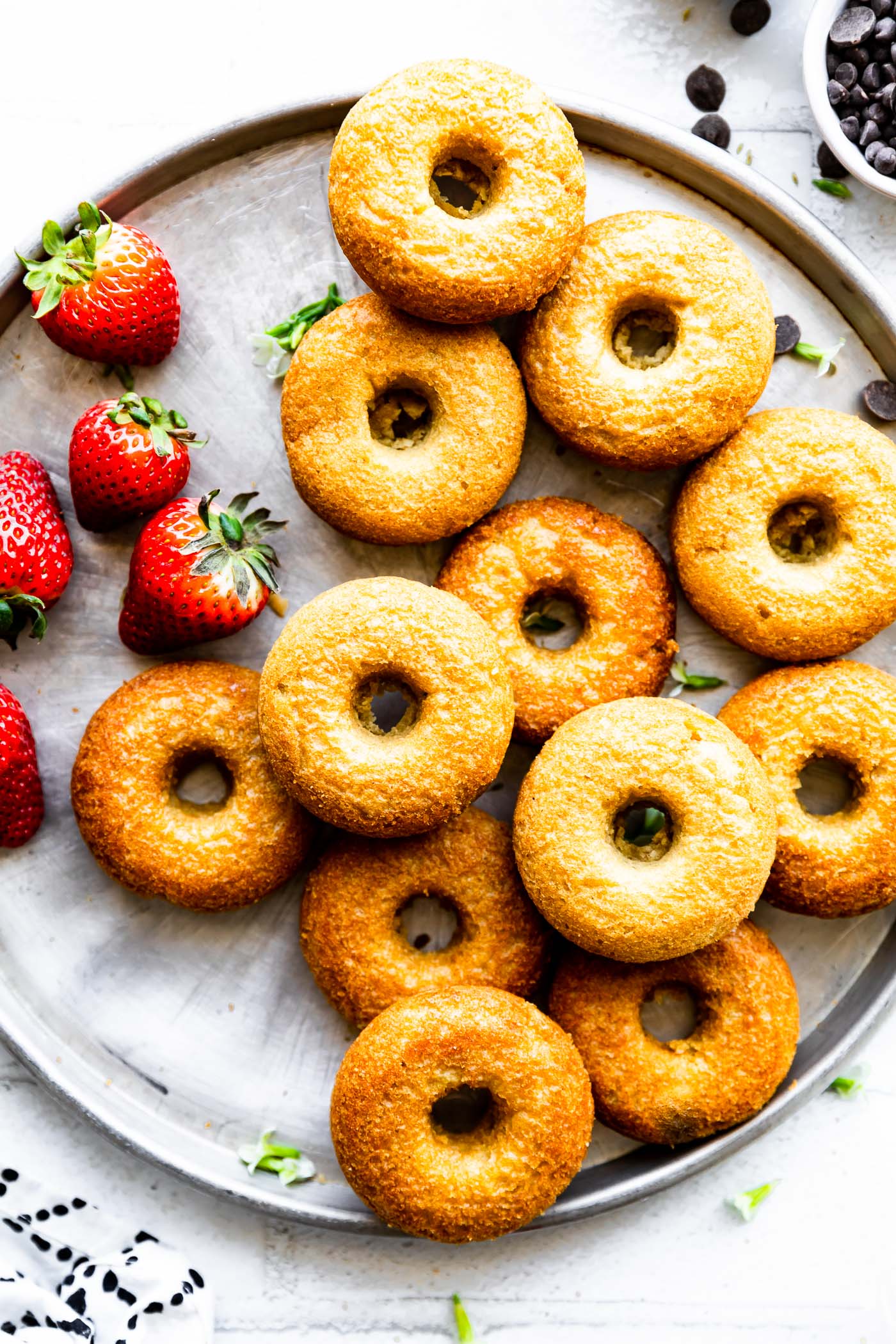 a plate full of unglazed baked vegan donuts with strawberries on the side