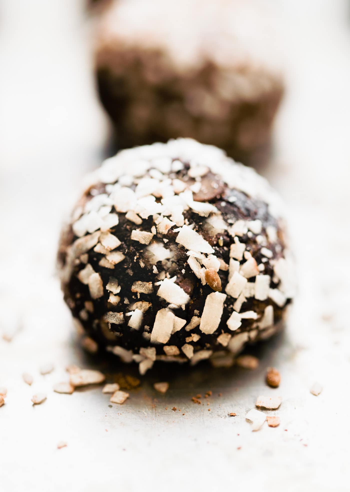 a coconut chocolate protein ball topped with coconut flakes