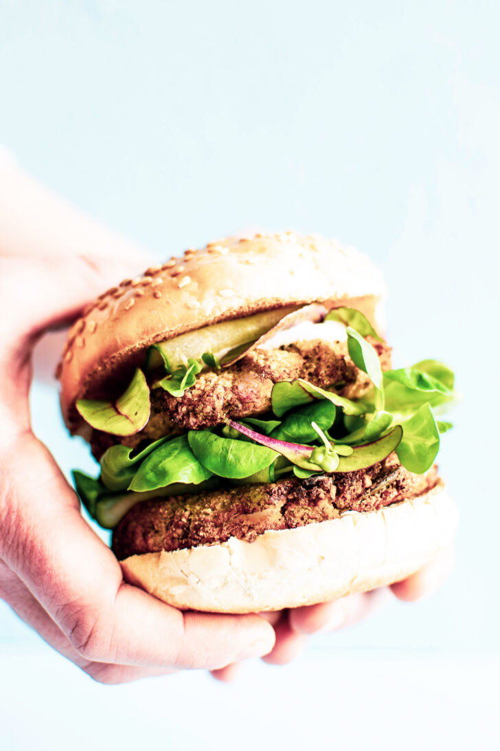 woman's hand holding a vegan veggie burger