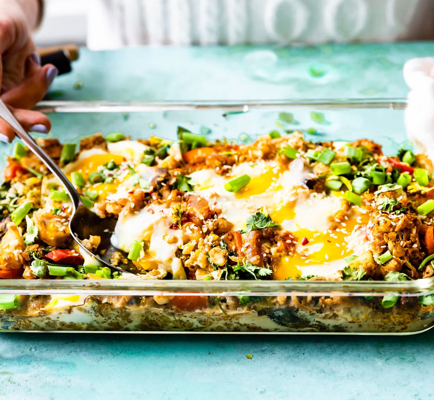 Side view of baking dish filled with cauliflower fried rice with baked eggs on top.