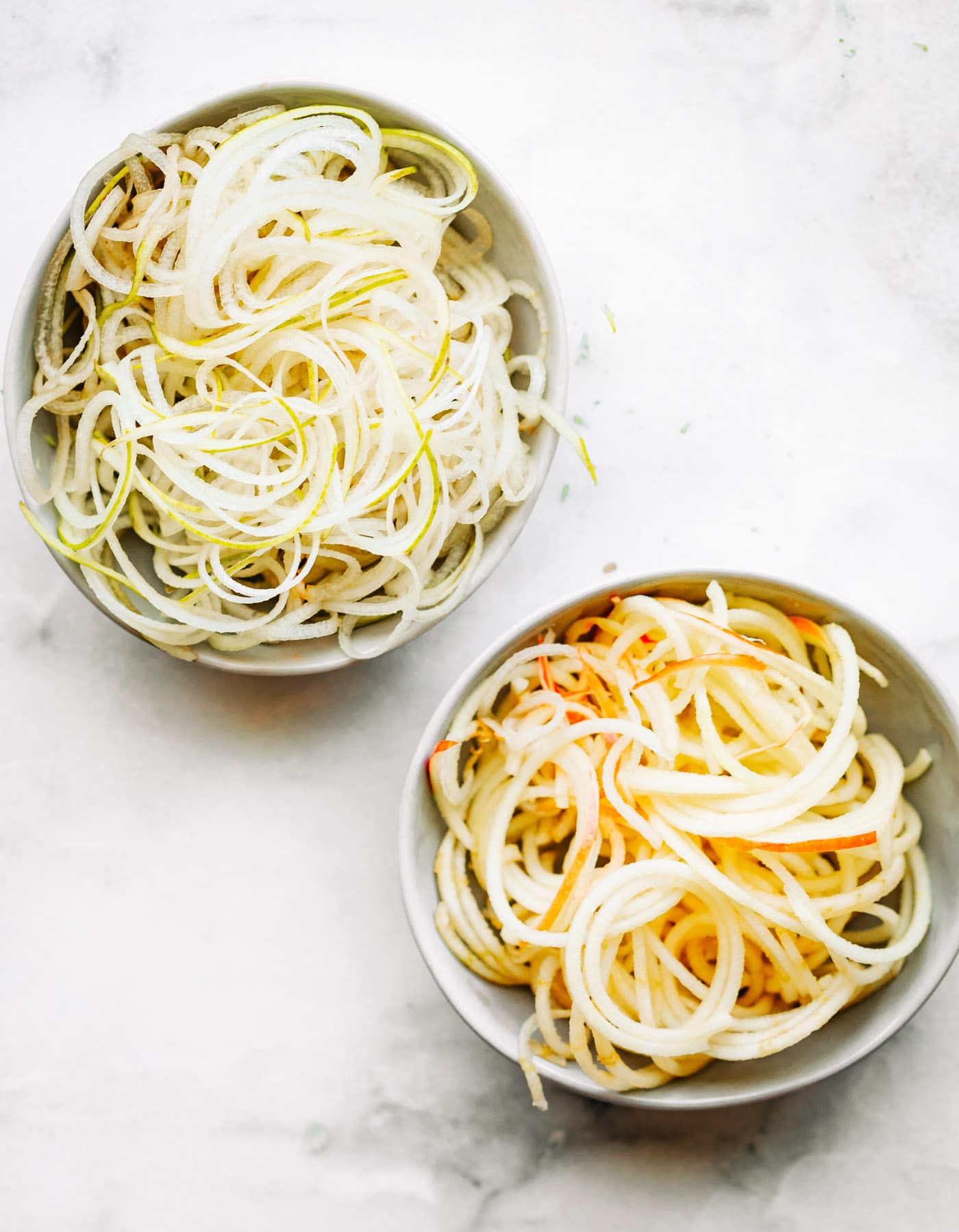 Two bowls filled with pear noodles and apple noodles.