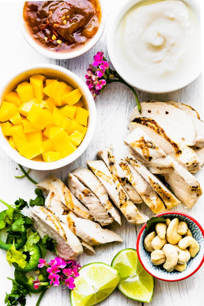 ingredients to make a curried chicken salad recipe arranged together on white cutting board