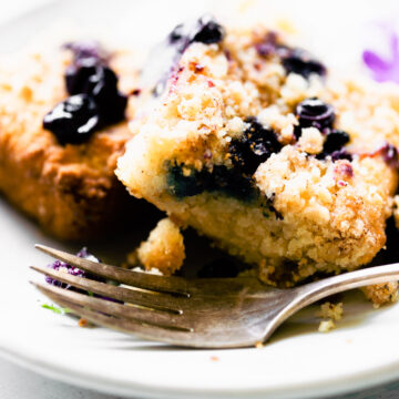 Two squares of blueberry buckle cake on white plate.