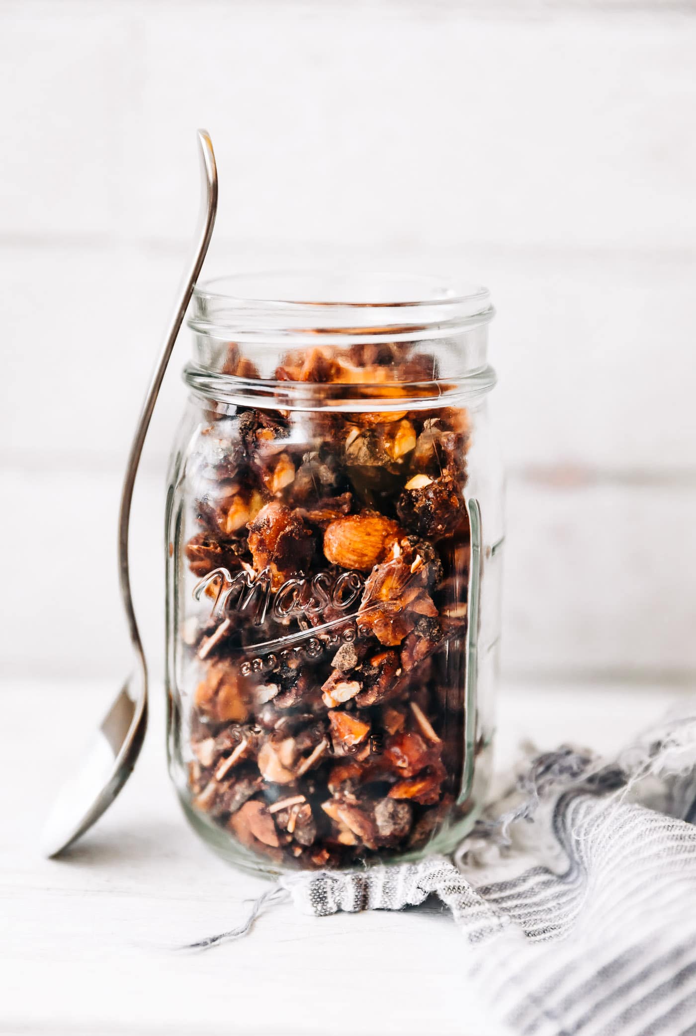 Grain free granola clusters in mason jar with spoon resting on side of jar.
