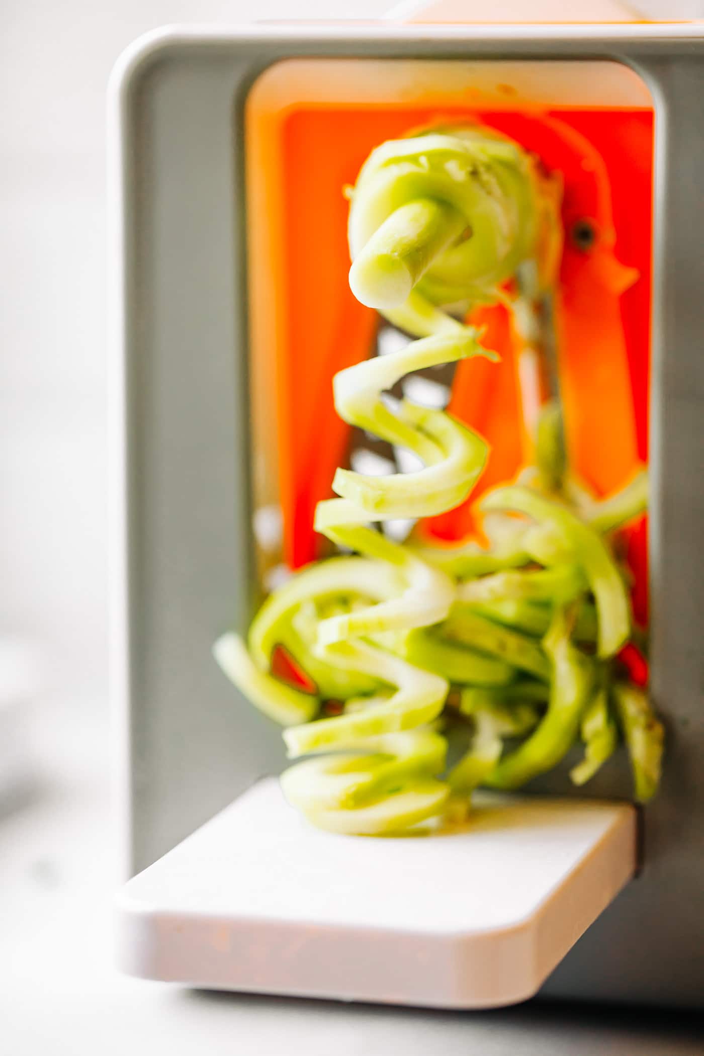 Zucchini coming out of spiralizer for veggie noodles.