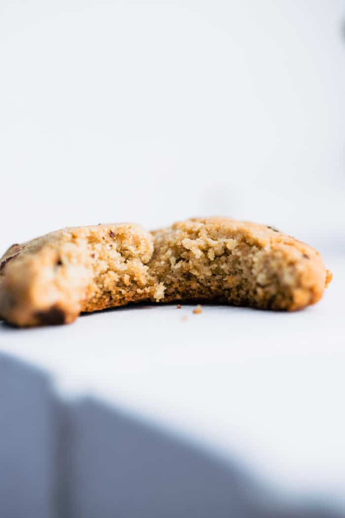 Close up view almond flour cookie with chocolate chips with big bite from the side to show inside texture.