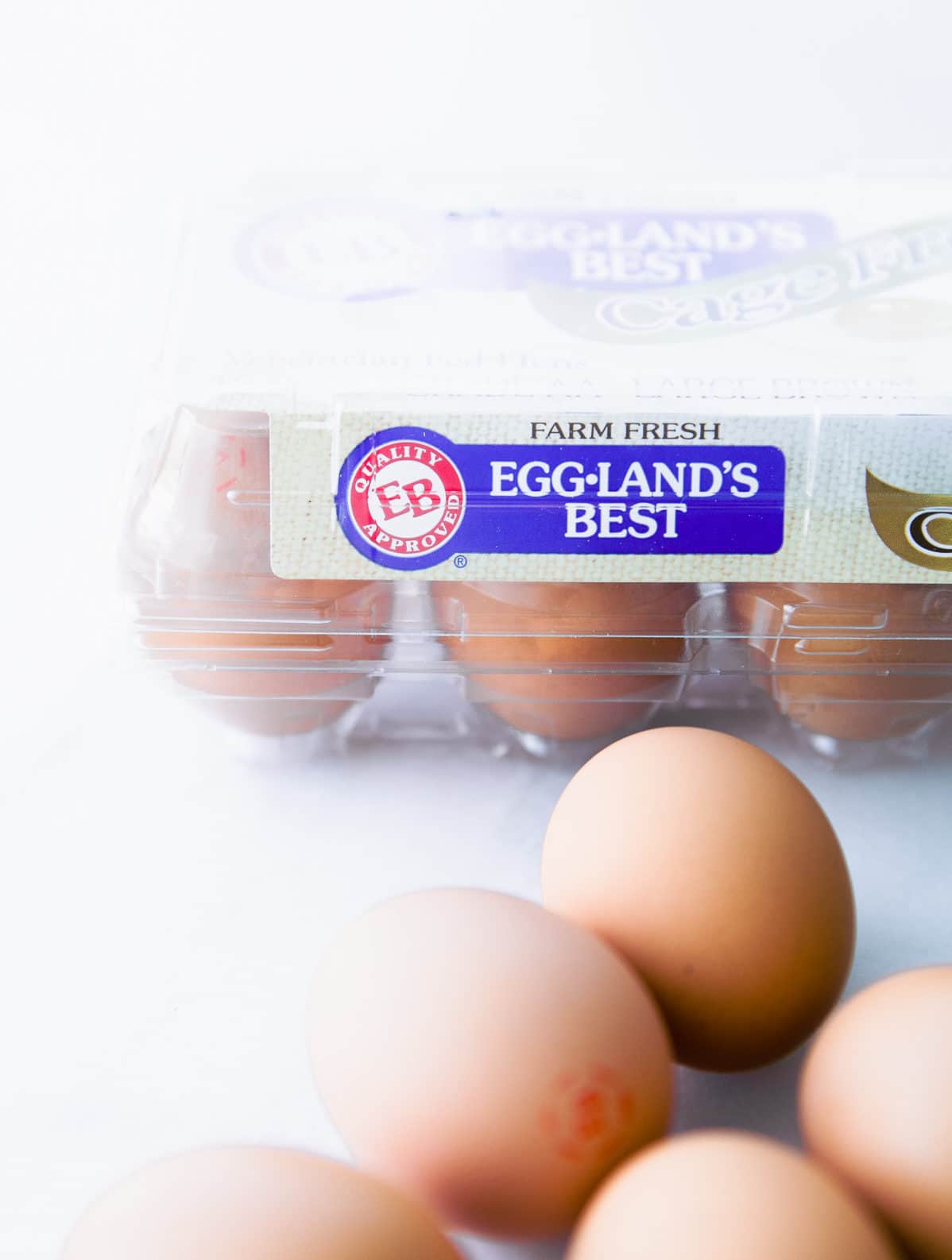 Eggland's Best egg carton in background with brown eggs on counter in foreground.