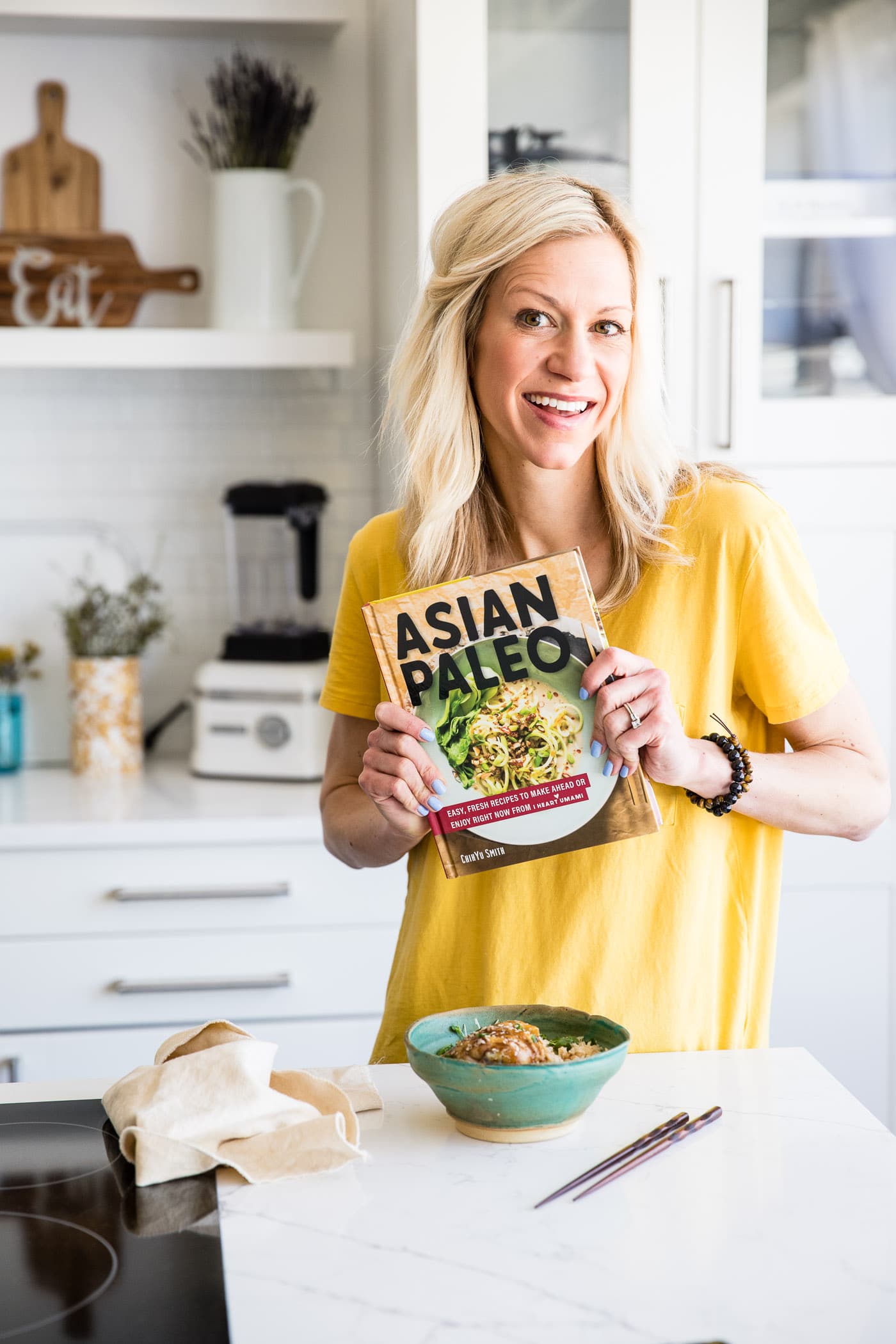 woman smiling holding a cookbook titled Asian Paleo