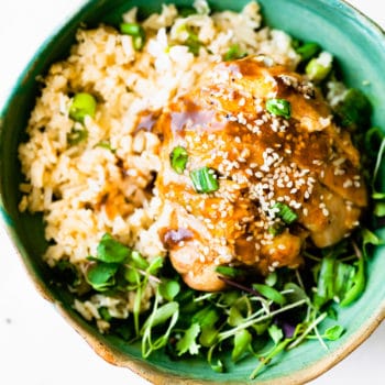 Teriyaki chicken served over bed or rice and greens in turquoise bowl