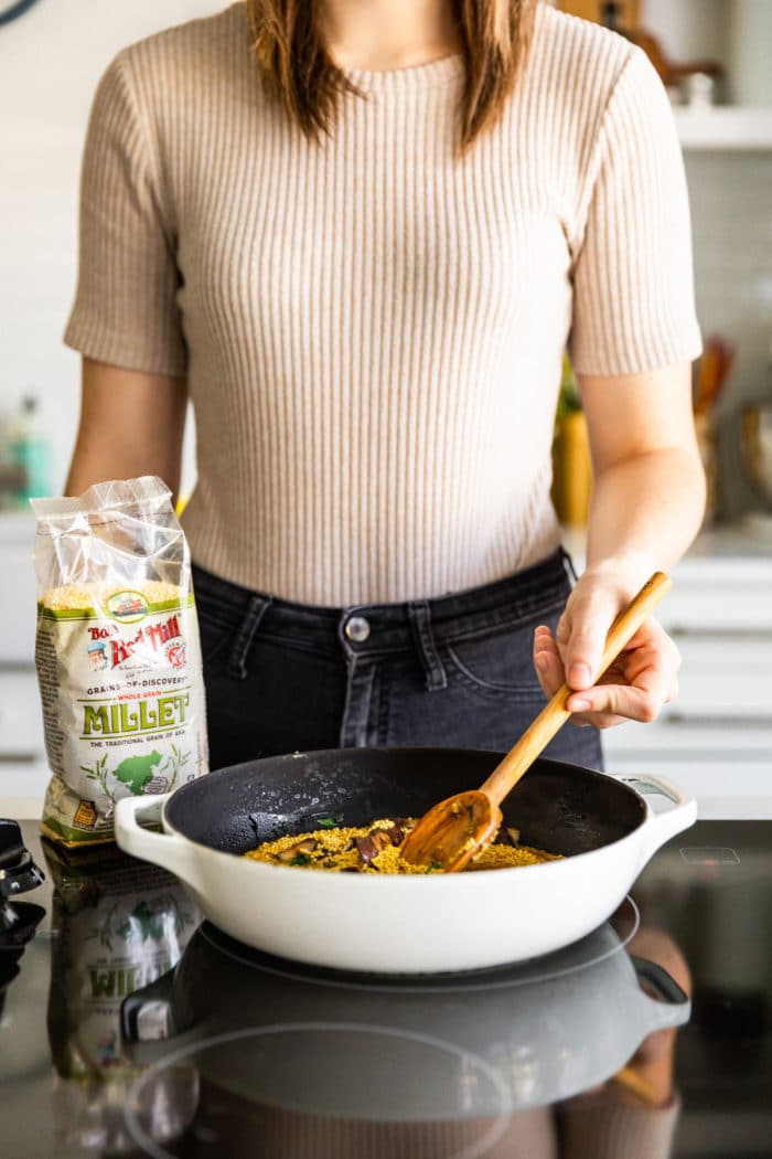 woman cooking millet breakfast bowl on stovetop