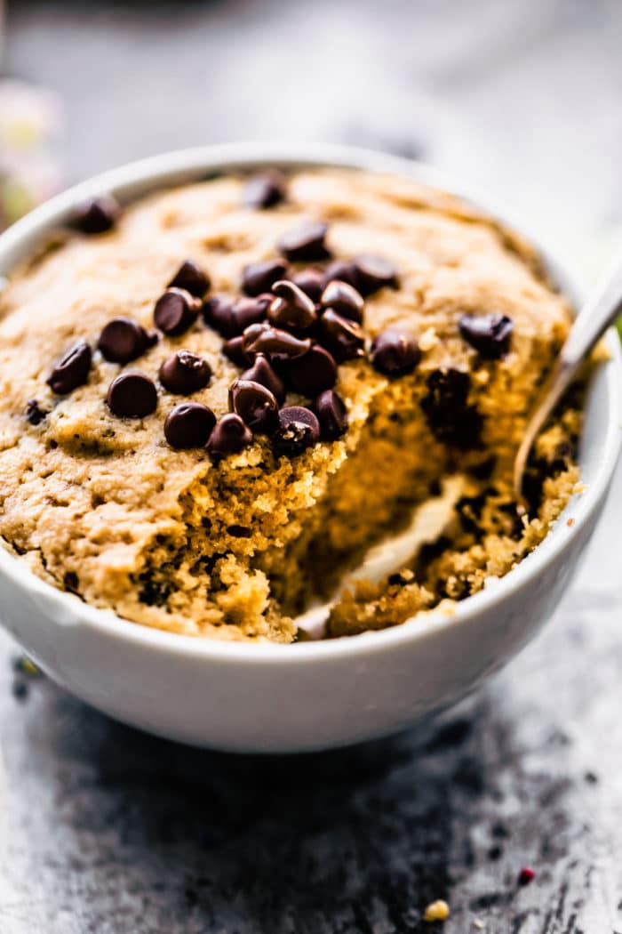 vanilla mug cake topped with chocolate chips, a bite taken out