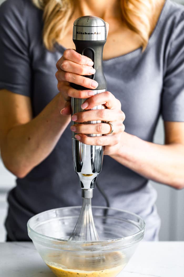 a woman using an immersion blender to blend low carb pancake batter