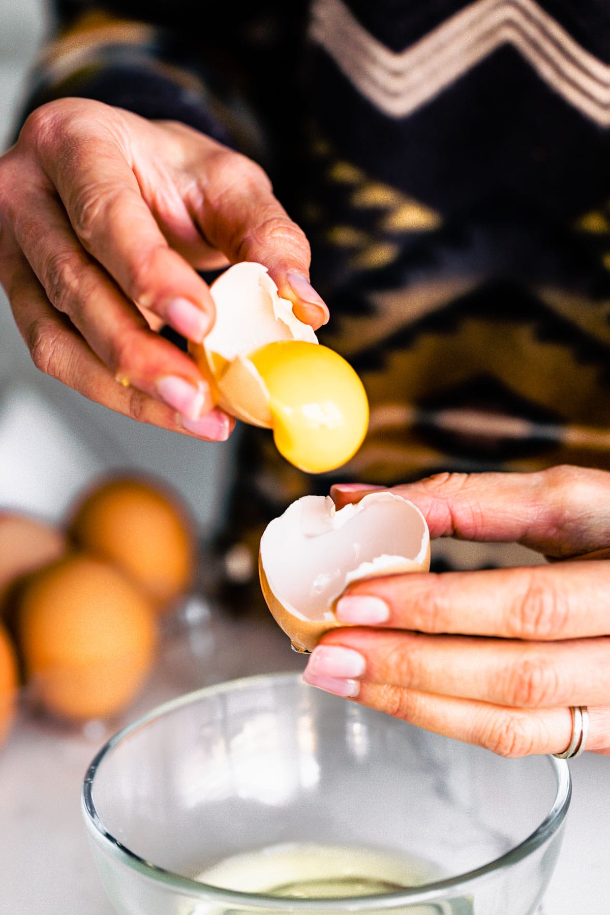 woman holding cracked egg and separating egg yolk