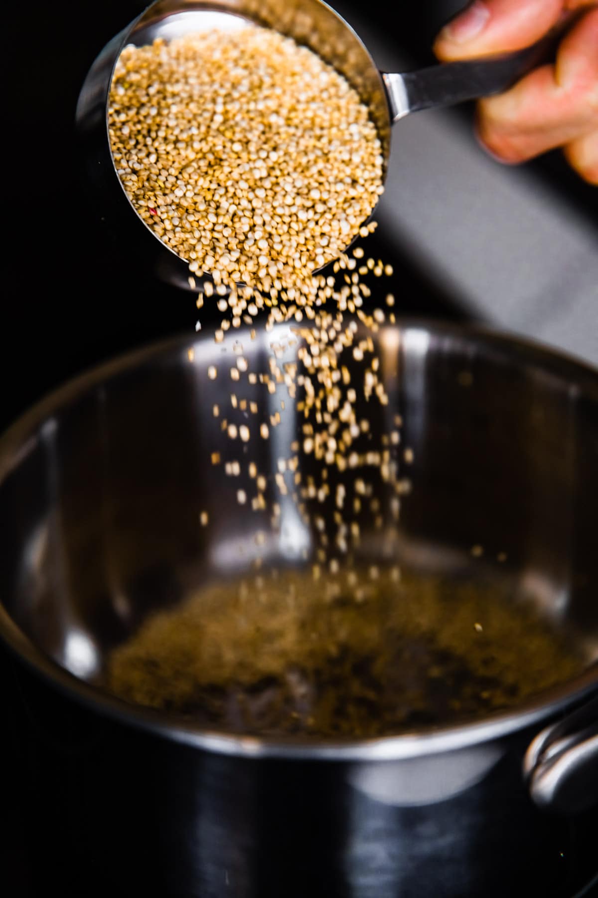 uncooked quinoa grains being poured into an instant pot