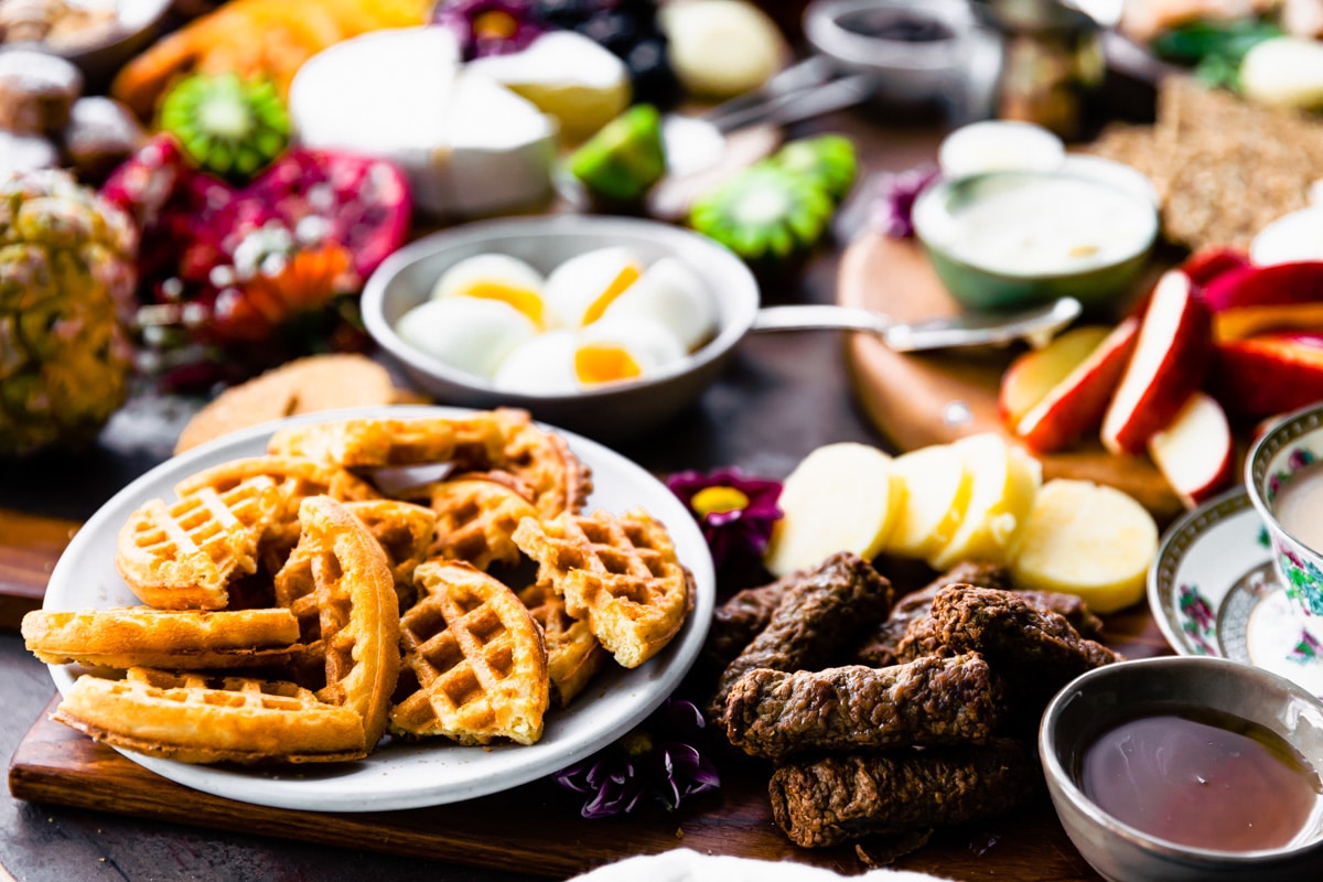 Brunch charcuterie boards filled with waffles, sausages, hard boiled eggs, and fresh fruit.