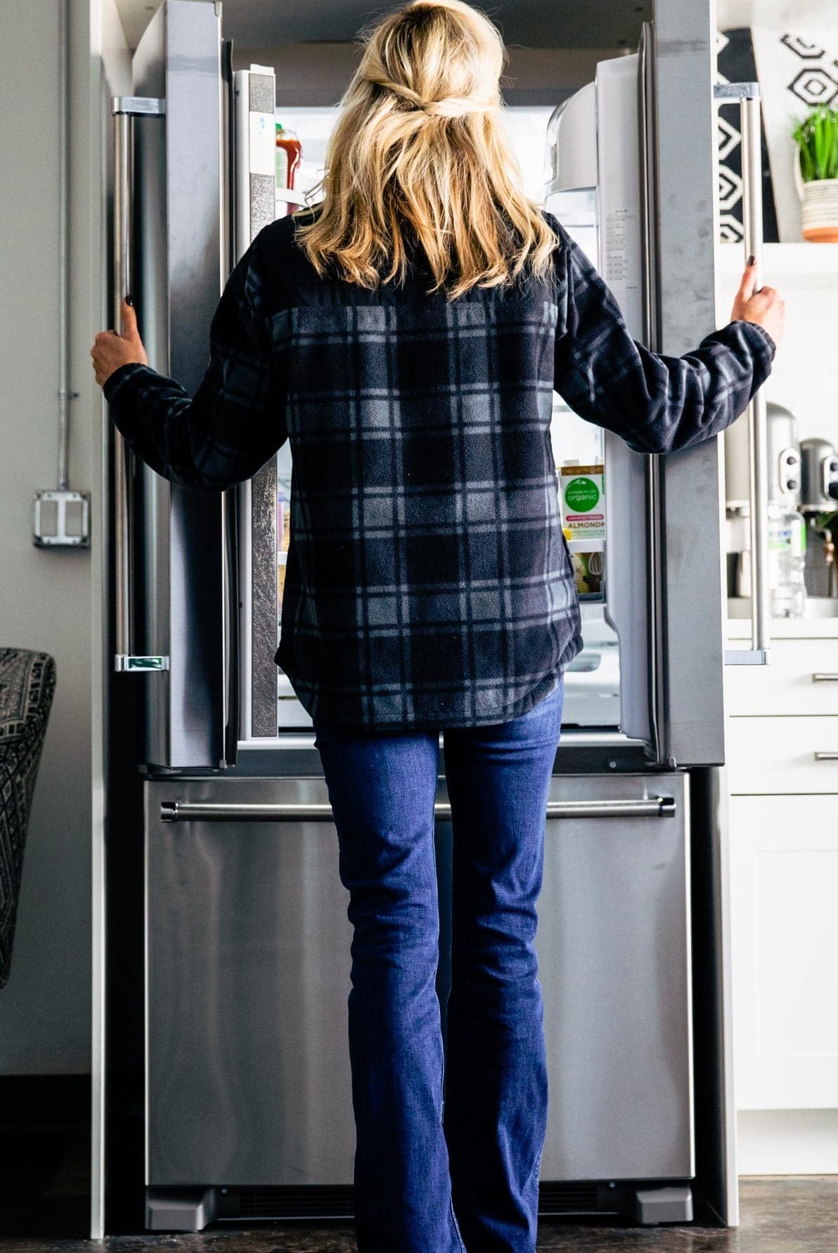 A woman standing in front of silver KitchenAid refrigerator with double doors open
