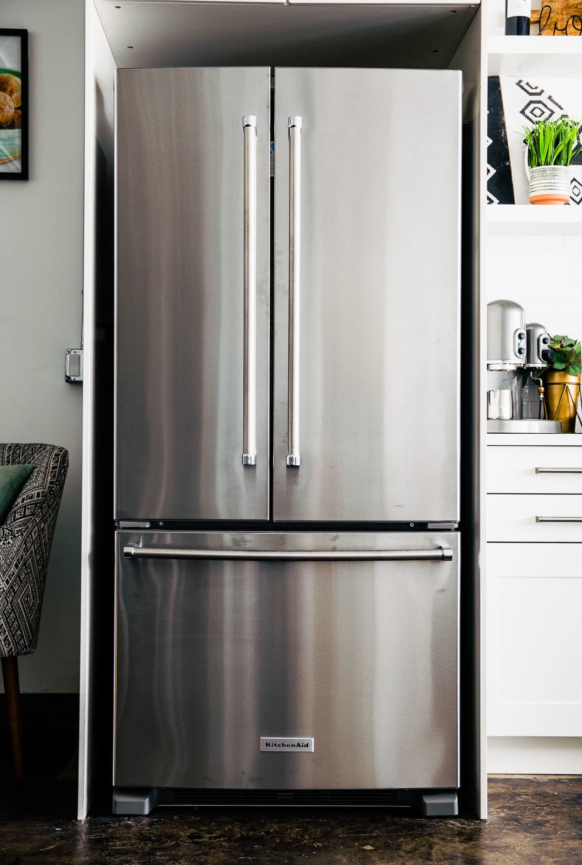 Silver KitchenAid double door refrigerator with white cupboards around