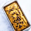 loaf of vegan pumpkin bread studded with dark chocolate chips