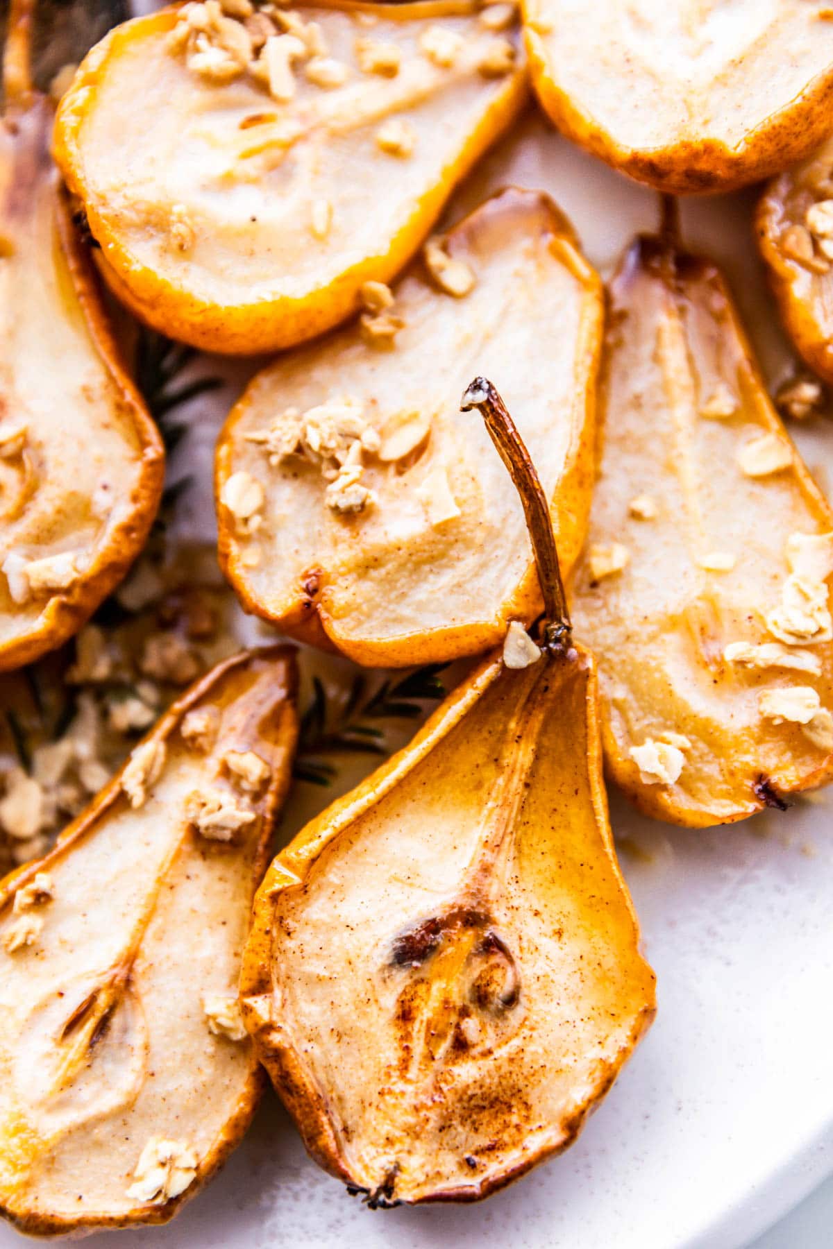 Close up overhead view baked pears with maple glaze and sprinkle of granola on top.