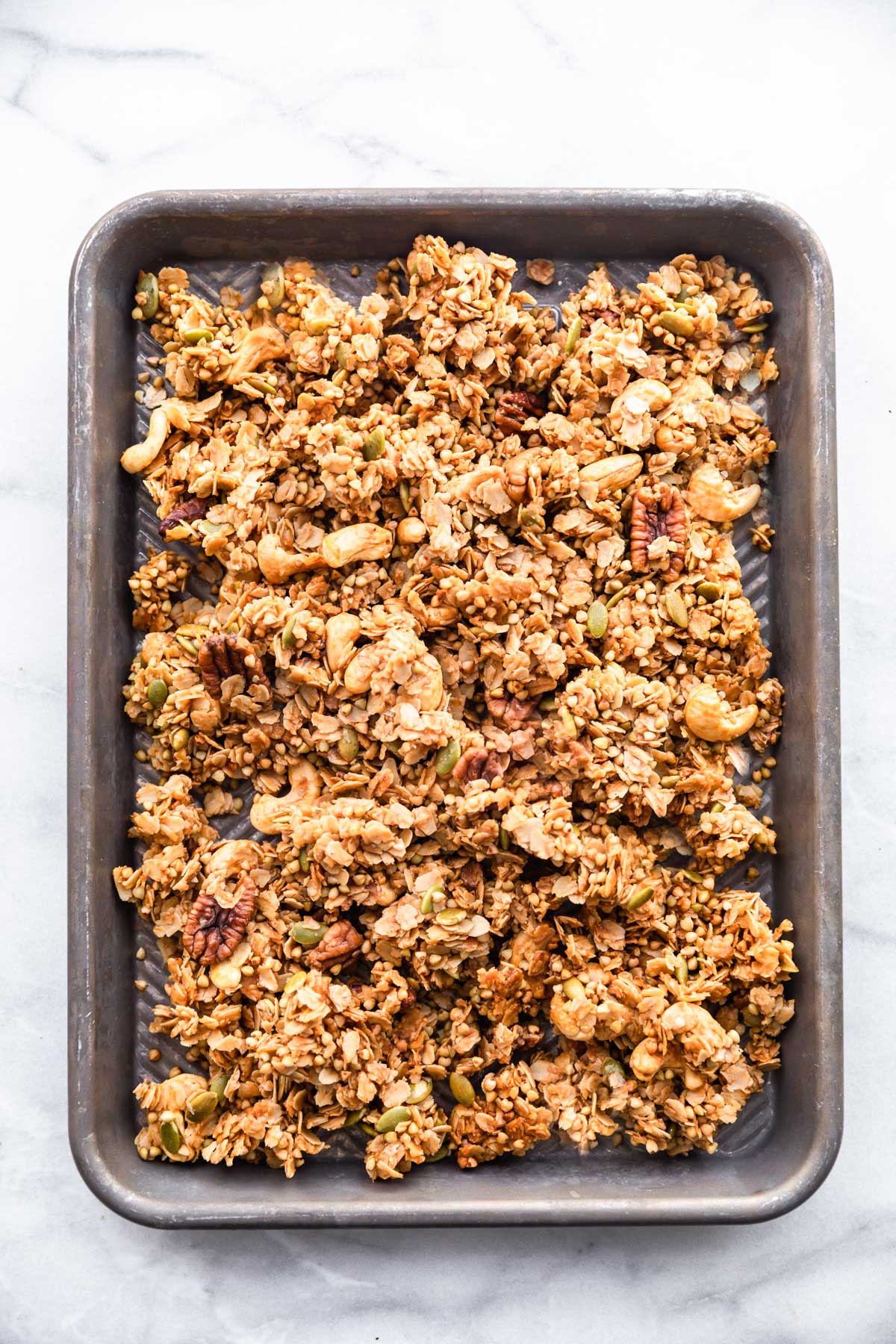 Maple buckwheat granola spread evenly on baking sheet ready to be baked