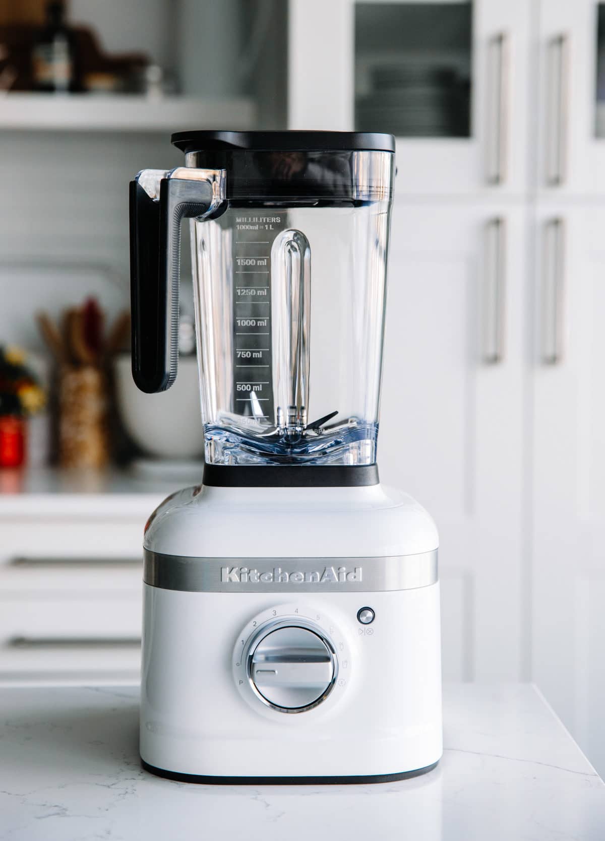 A Kitchen Aid high speed blender with white base on marble countertop.