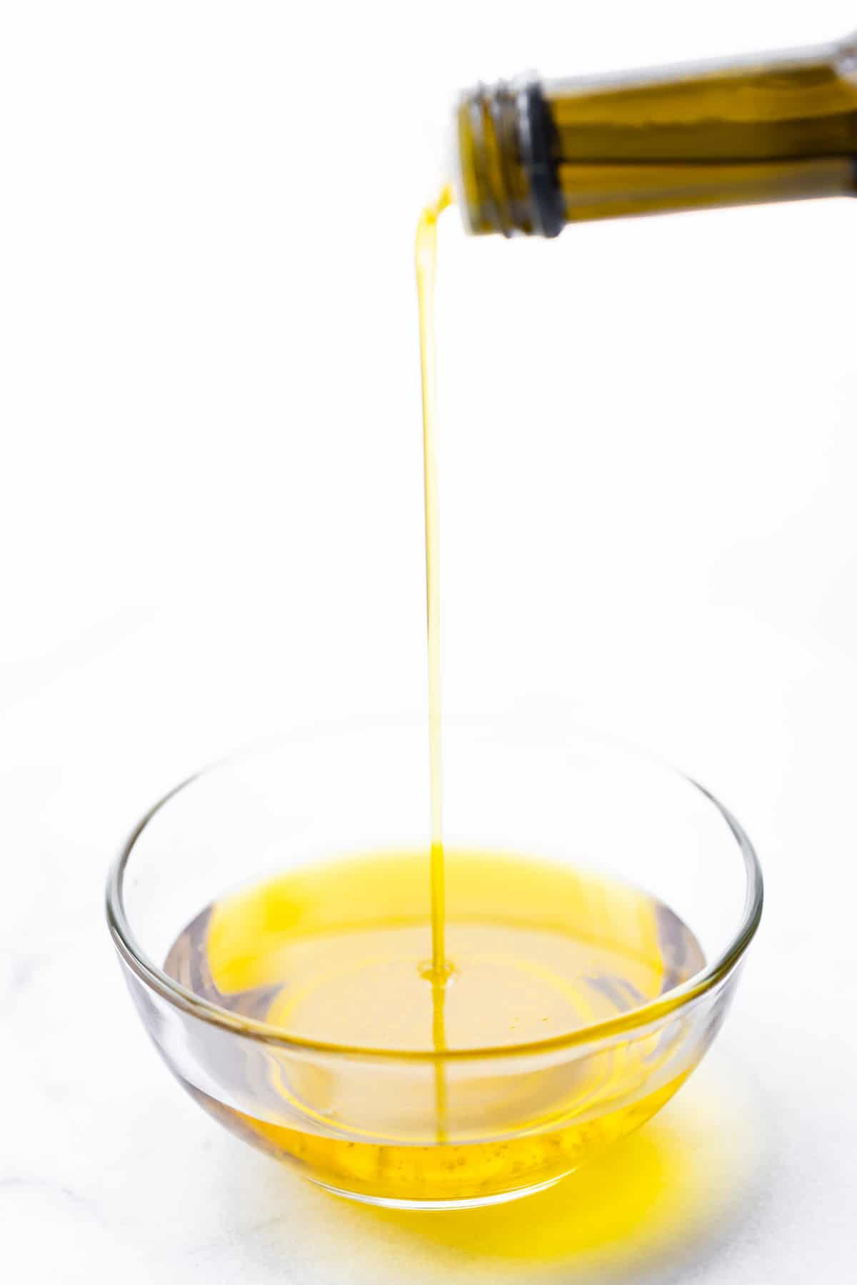 jar of olive oil being poured into bowl
