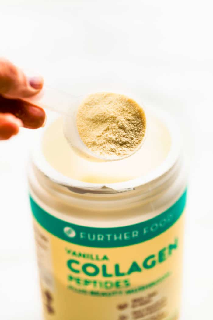A container of Further Foods collagen with scoop holding serving of collagen over jar.