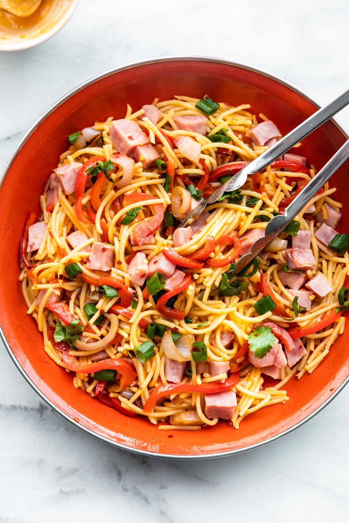 noodles, ham and vegetables in orange bowl