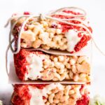 Three white chocolate crispy treat bars with dried raspberries stacked on each other, tied together with twine.