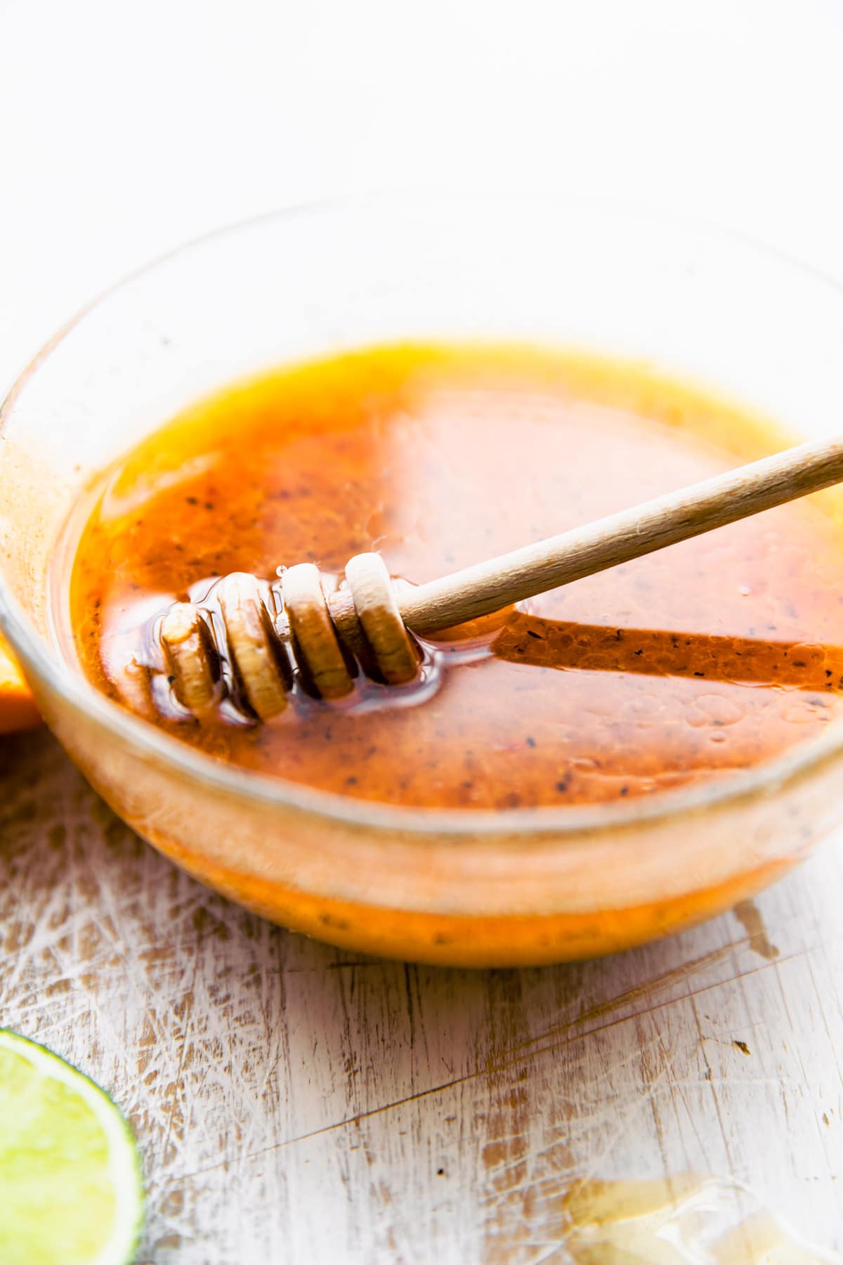 Sweet and spicy marinade for broiled shrimp in bowl with honey dipper in marinade.