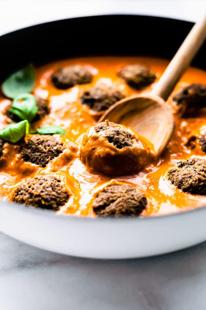 close up: vegan mushroom meatballs in skillet of orange colored pasta sauce