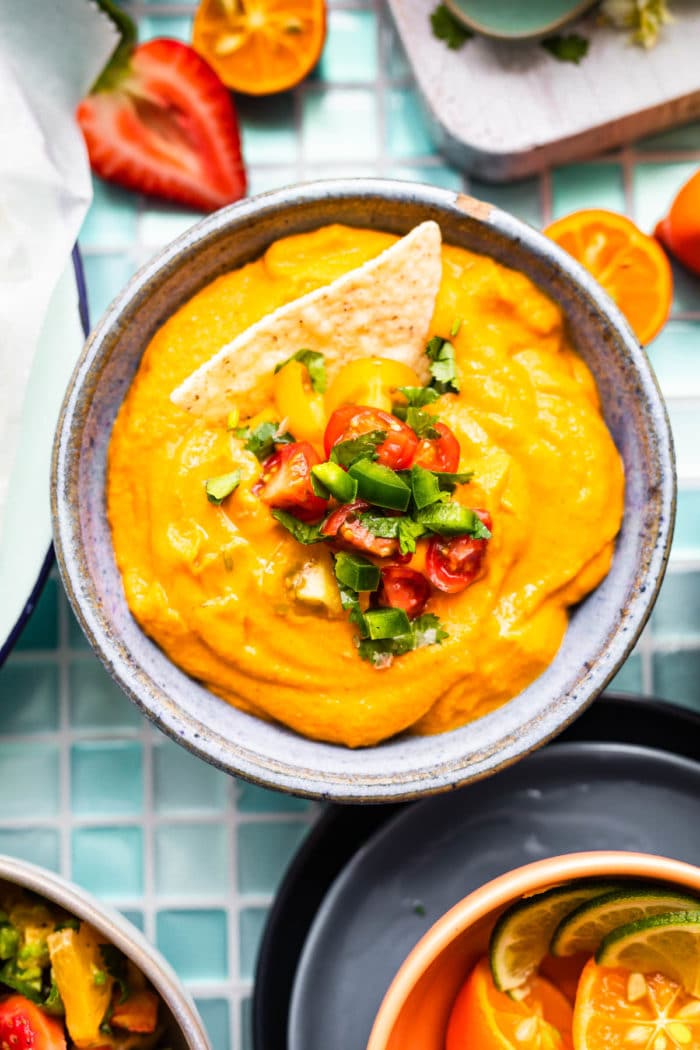 overhead image: bowl of vegan con queso garnished with fresh pico de gallo