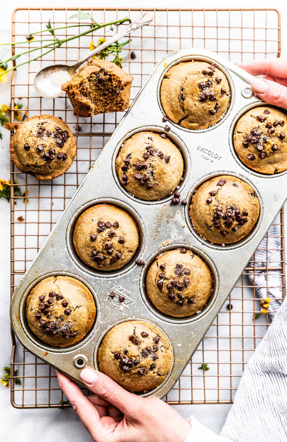 muffins in a pan with hands holding edges