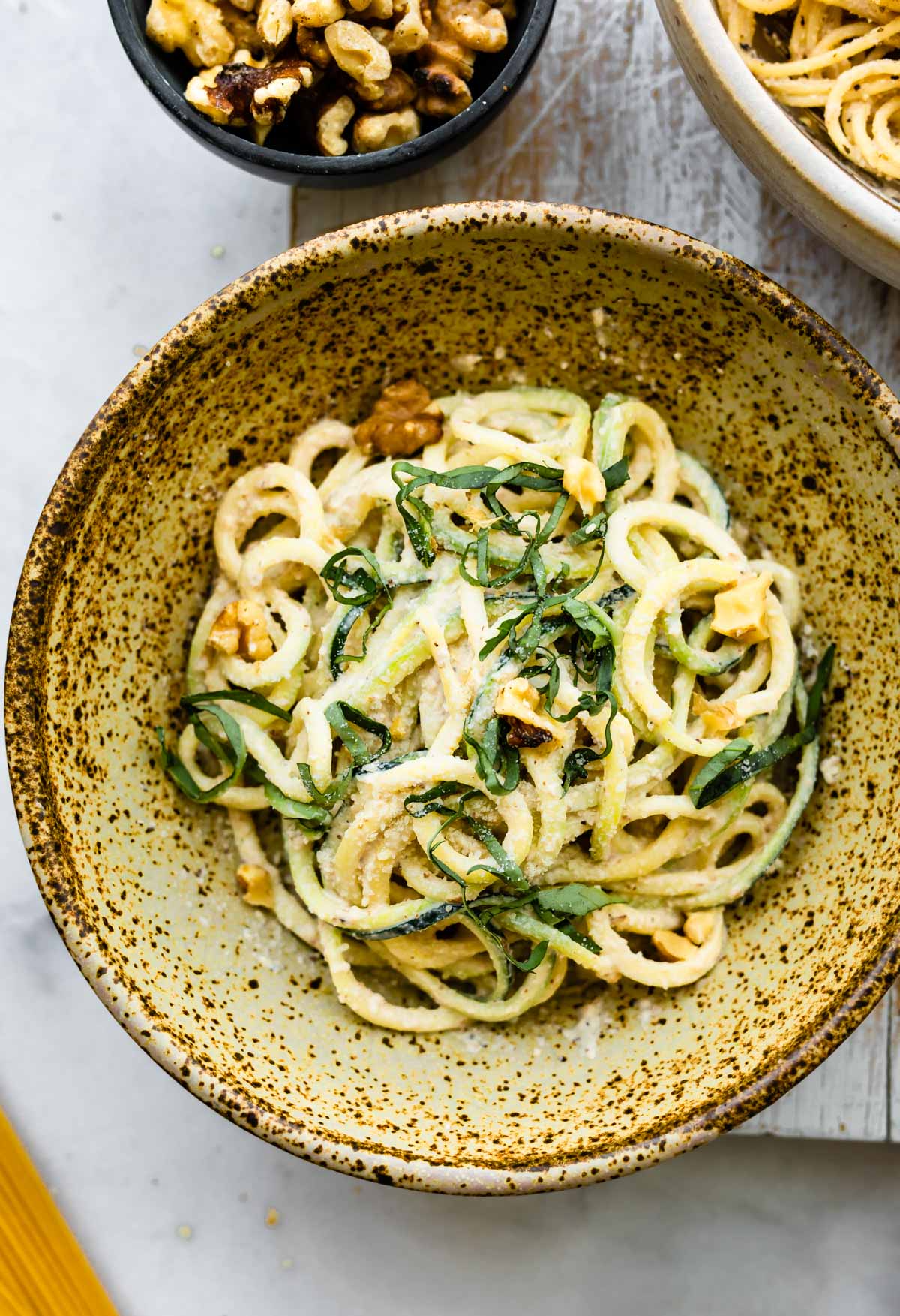 overhead photo shows bowl of zucchini noodle pasta with vegan garlic sauce