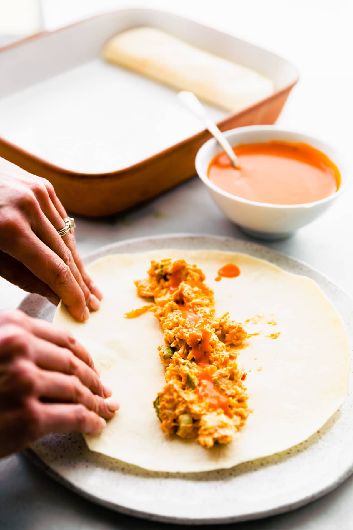 woman's hands rolling tortillas for easy enchilada recipe