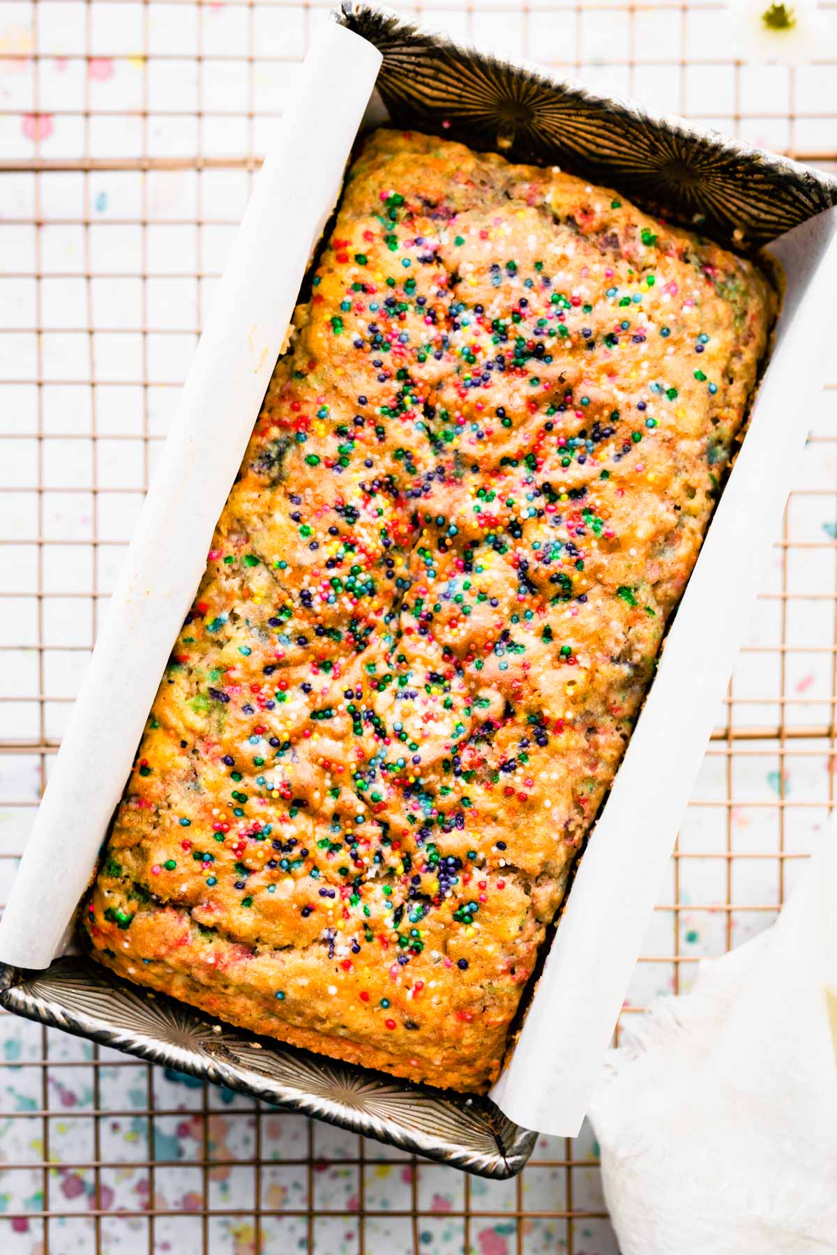 loaf of vegan ice cream bread with colored jimmies on top in silver loaf pan