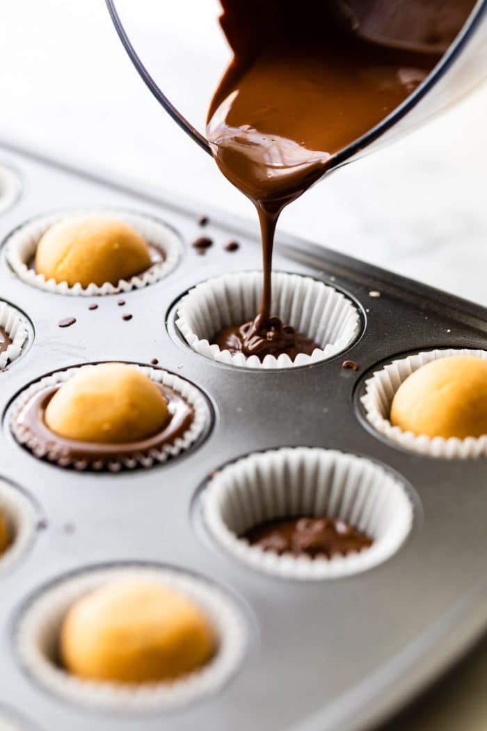 making vegan candy: pouring melted chocolate into parchment paper lined mini muffin cups