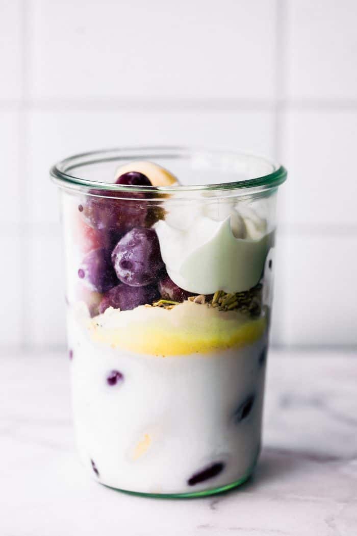dairy free yogurt, grapes, milk, and protein all in a large cup to make a smoothie.