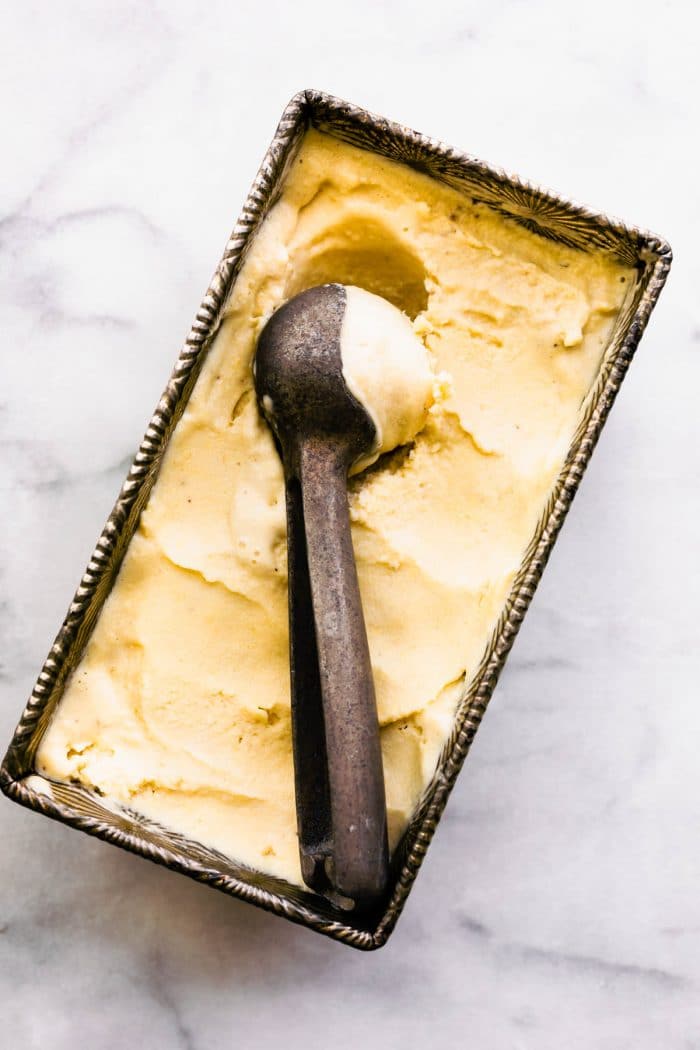 overhead image: scooping frozen banana vegan ice cream from a loaf pan