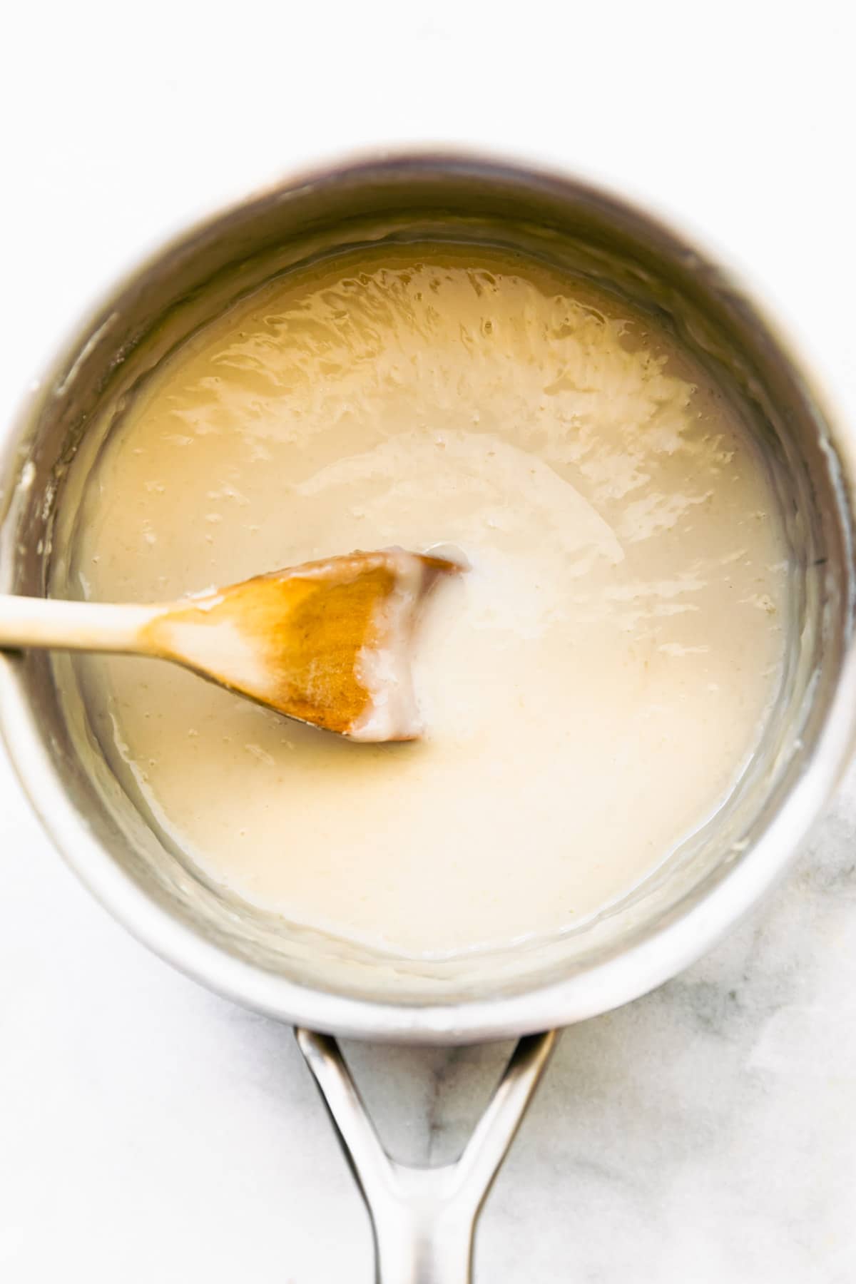stirring pot of dairy free sweetened condensed milk in saucepan