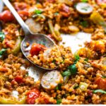 baked Mexican cauliflower rice with chorizo on a sheet pan, with some on a serving spoon