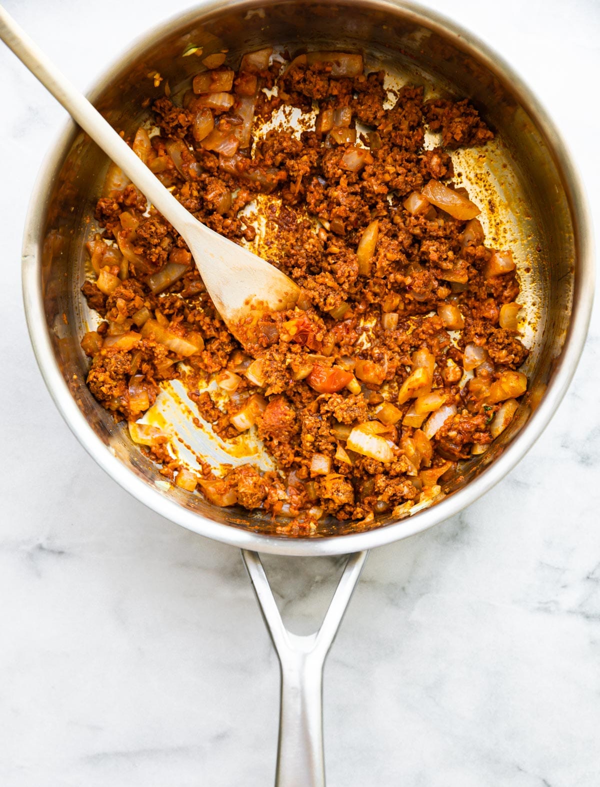 overhead photo: wooden spoon in large skillet with ground chorizo