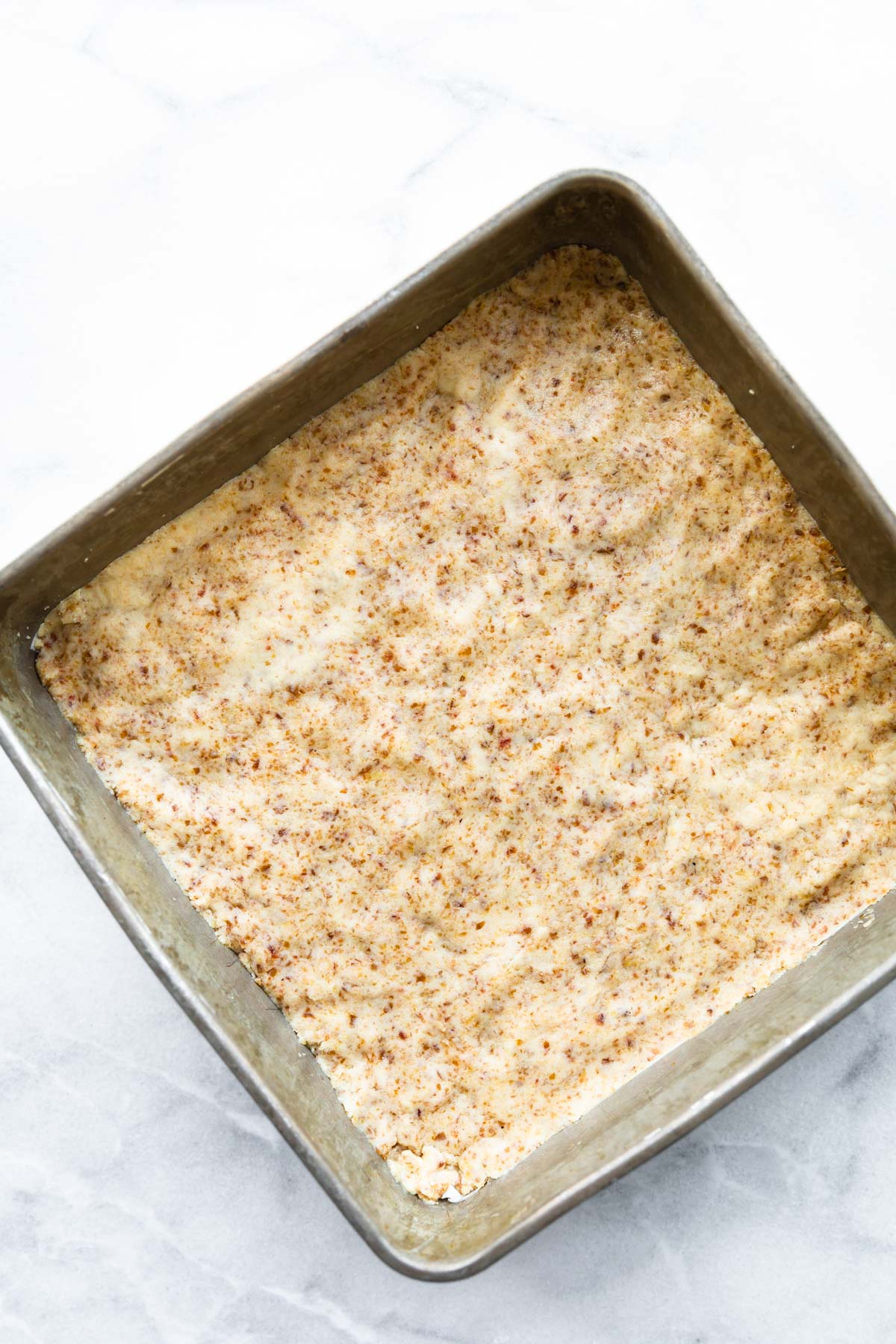 overhead: paleo flour crust in a pan for vegan dessert bars