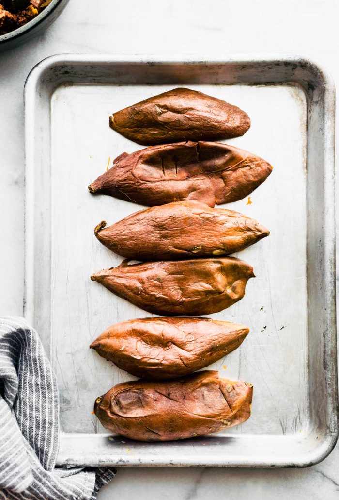 hollowed out sweet potatoes placed upside down on a baking sheet