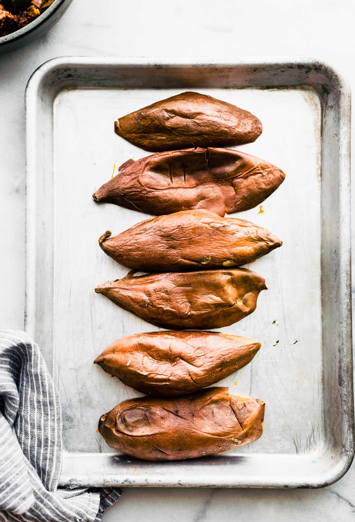 hollowed out sweet potatoes placed upside down on a baking sheet